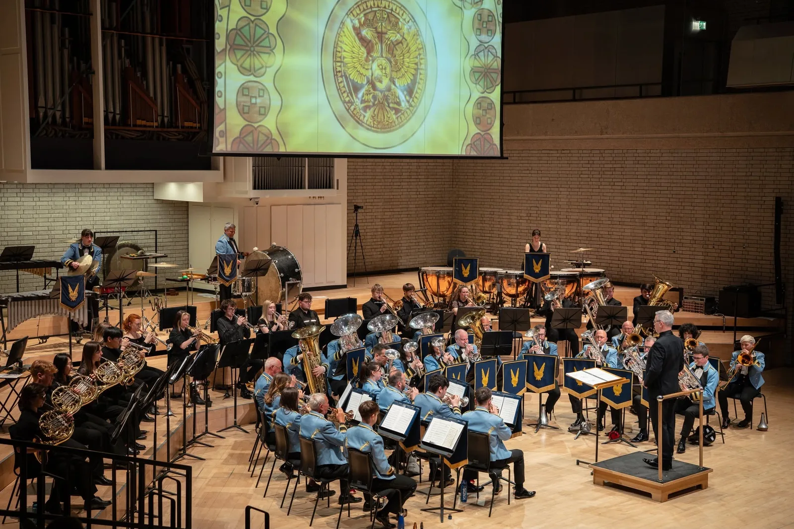 The KNDS Fairey Band and percussion section performing beneath synchronised animation at the Royal Northern College of Music